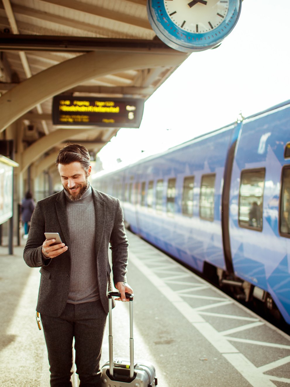 Homme attendant le train à la gare en regardant son mobile